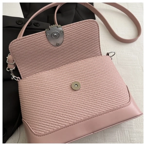 Detail of pink shoulder bag showing woven texture flap and silver magnetic metal buckle