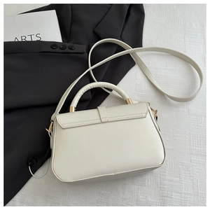 Detail of minimalist cream leather handbag with gold metal hardware and top handle strap