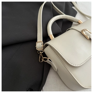 Detail of white PU leather handbag featuring a gold metal lock and a rounded top handle