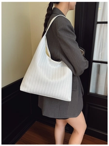 Gros plan sur la texture tissée blanche d'un sac à bandoulière minimaliste aux détails en V