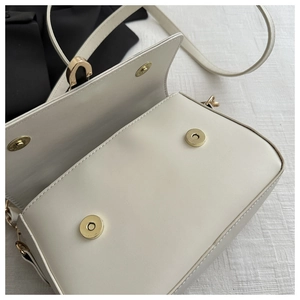 Detail of off-white crossbody bag featuring double magnetic closure and gold-tone hardware