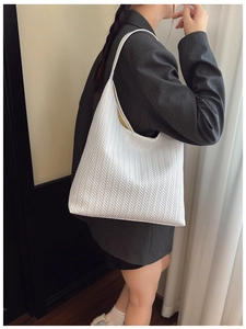 White woven shoulder bag shown with a grey blazer for a stylish commuter look