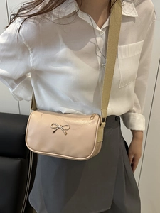 Chic beige crossbody bag with metallic bow detail and wide shoulder strap for women