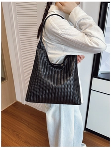 Detail of woven texture and large capacity of the black faux leather tote bag