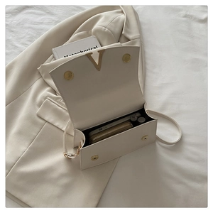 Top view of open cream white shoulder bag showing interior space for wallet and lipstick