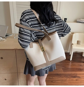 Detail view of the large capacity contrast color tote bag showing shoulder strap and gold clasp