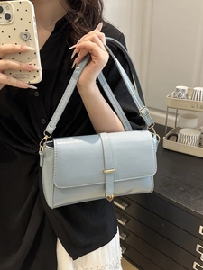Light blue glossy leather shoulder bag with gold heart pendant shown in mirror selfie