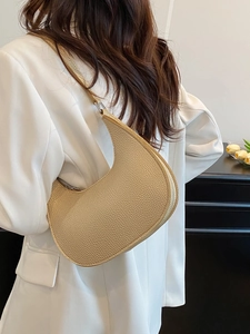 Beige crescent shoulder bag in lychee texture leather worn by a model for daily commute