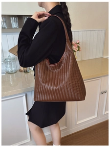 Close-up of the intricate brown leather weaving detail and slim strap of this hobo bag