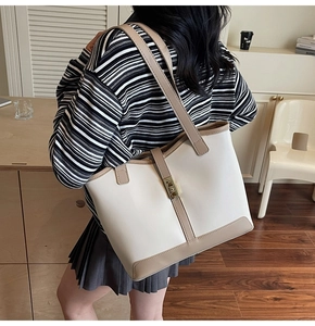 Detail of the minimalist tote bag showing contrast stitching and golden metal twist lock