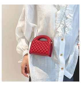 Detail of red quilted mini handbag with glossy finish and silver chain strap for women