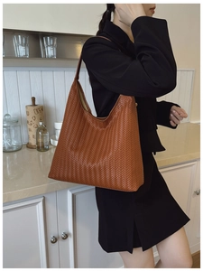 Gros plan sur la texture tressée caramel d'un sac à bandoulière hobo minimaliste