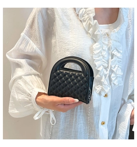 Detailed close-up of a quilted black mini bag with top handle and silver chain strap