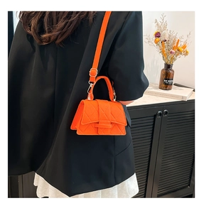 Detail of orange quilted felt crossbody bag with diamond texture and shoulder strap