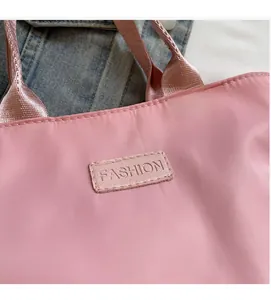 Detail der rosa Nylon-Einkaufstasche mit 'FASHION'-Label und gewebtem Tragegriff
