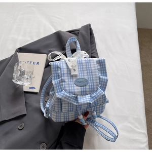 Detail of blue plaid mini backpack featuring lace bow decoration and ruffled trim