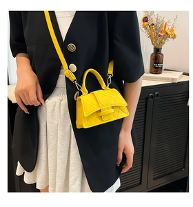 Detailed view of yellow quilted mini bag with adjustable strap in home setting