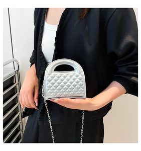 Detail of silver mini chain bag featuring quilted texture and metallic finish on model