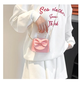 Detailed texture of pink litchi leather bag with pearl handle and bow accent