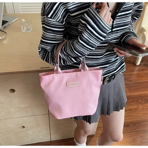 Detailed shot of pink nylon tote bag with metallic handles and FASHION logo label