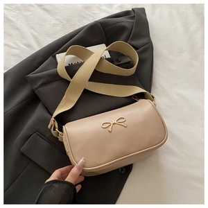 Détail du sac bandoulière beige avec boucle nœud dorée et large bandoulière en toile