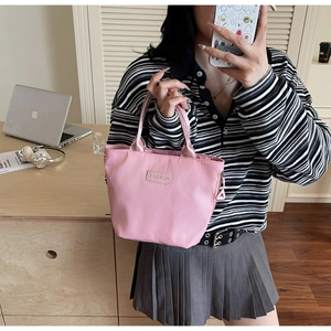 Detail of pink waterproof nylon tote bag with Fashion label in a casual lifestyle setting