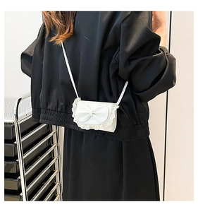 Close-up of mini white handbag featuring a large 3D bow and delicate lace trim details