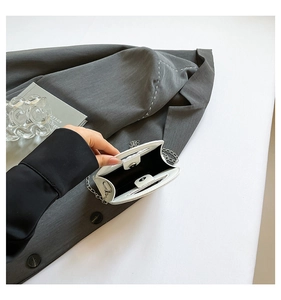 Detailed view of white square handbag interior with magnetic closure and silver chain strap