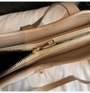 Detail of premium gold-tone zipper and beige faux leather stitching on large tote bag