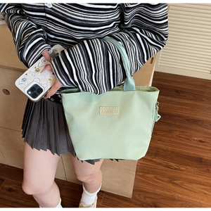 Detail of light green minimalist handbag with fashion patch and metallic zipper