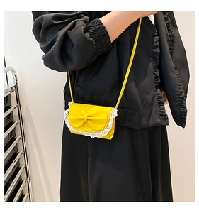 Detail of bright yellow mini crossbody bag featuring lace trim and a 3D bow decoration