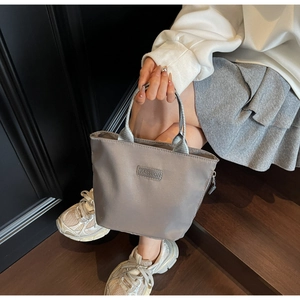 Detailed macro view of dark grey nylon tote bag with Fashion label and zipper