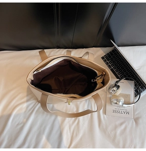 Spacious interior of a beige tote bag showing dark brown lining and zipper pocket