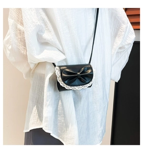 Detailed shot of mini black crossbody bag with large bow and white lace trim detail