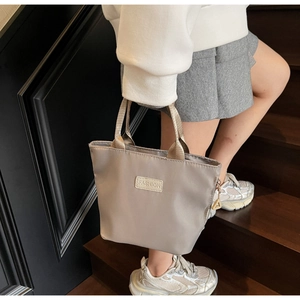 Close-up of gray fabric tote bag with Fashion label and satin handles on stairs