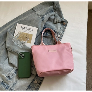 Detail of pink nylon tote bag with fashion label on white bedding and denim background