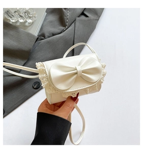 Détail d'un sac blanc en cuir avec bordures en dentelle et grand nœud élégant