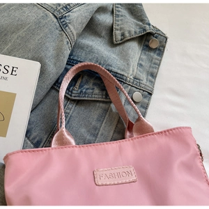 Close-up of pink nylon tote bag featuring fashion label and premium metal zipper detail