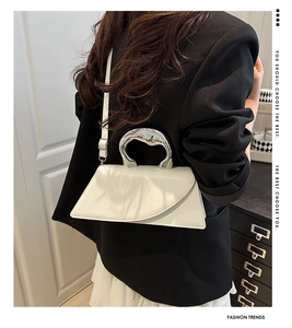 Dettaglio del manico in metallo argentato sulla borsa trapezoidale in pelle bianca