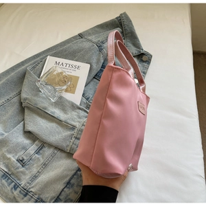 Close-up of pink nylon handbag with a decorative Fashion leather label in a lifestyle setting