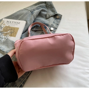 Detail of pink nylon tote bag showing wide bottom structure on a lifestyle background