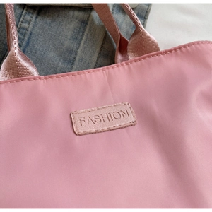 Close-up of pink nylon handbag fabric texture with fashion logo label and stitching