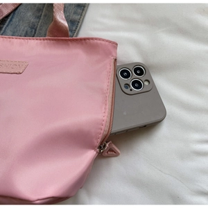Pink casual tote bag detail showing a side zipper pocket holding a large smartphone