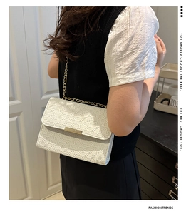 Détail du sac bandoulière crème avec texture tissée, chaîne dorée et fermoir en métal