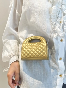 Golden quilted mini bag with metallic texture and chain strap worn by a model