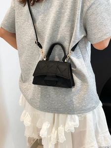 Elegant black quilted handbag with gold hardware shown as crossbody style on model