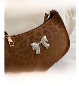 Gros plan du sac léopard avec ornement papillon en métal argenté et finitions dorées