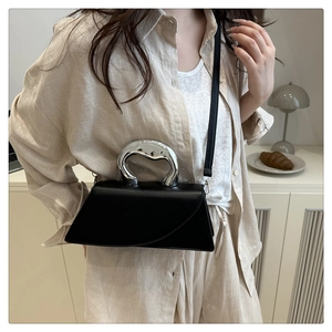 Detail of a black leather handbag with a unique silver liquid metal handle and crossbody strap
