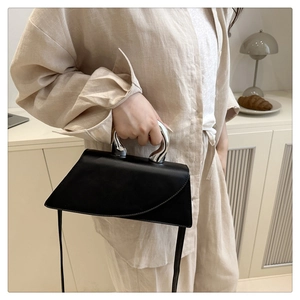 Detail of artistic silver horn handles and asymmetrical flap on black leather handbag