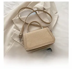Détail du sac à main beige en paille tressée avec fermoir argenté et texture fine